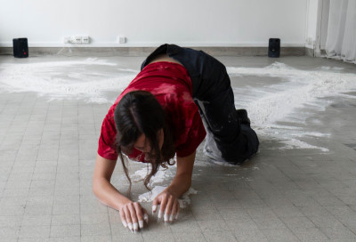 La danzatrice Elena Sgarbossa, carponi, lasciando una scia bianca al suo passaggio
