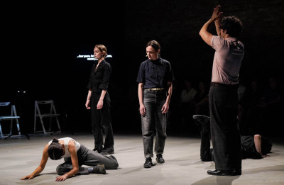 Cinque performer in scena, due a terra, tre in piedi
