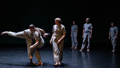 Alcuni danzatori in abiti grigi in scena