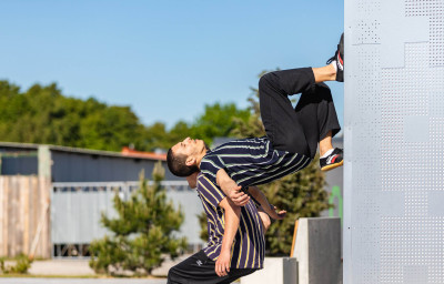 Un danzatore sulla schiena di un altro è spinto quasi a camminare sulla parete verticale