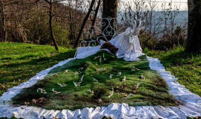 Installazione di una strana creatura bianca e tante lumachine su un prato verde